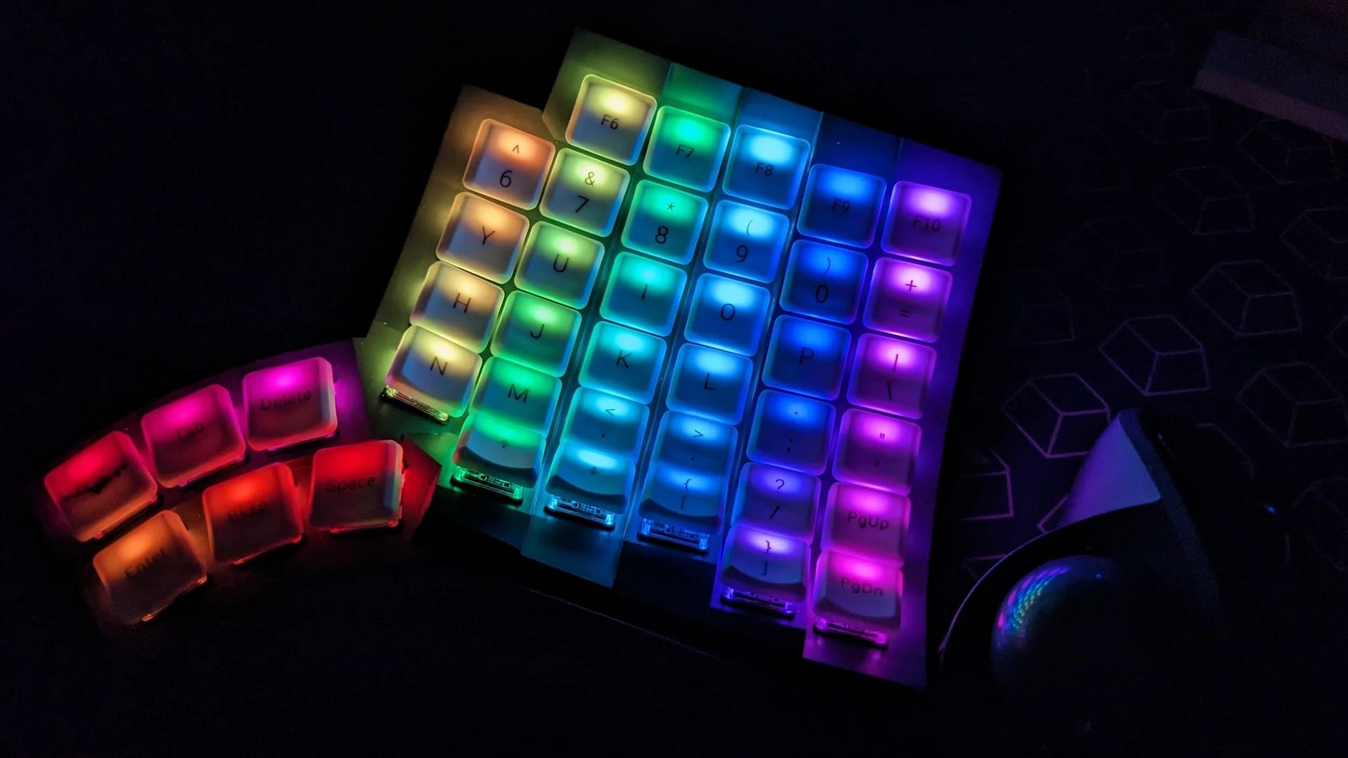The right half of the Glove80 in the dark, keys illuminated in rainbow colors