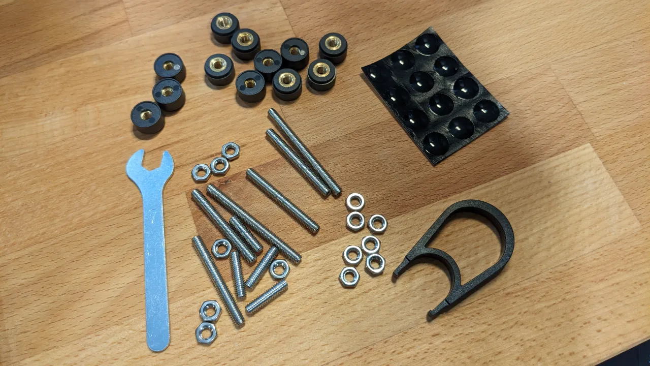 An array of customization hardware, including nuts and bolts in a range of sizes, along with a wrench and a keycap puller tool.